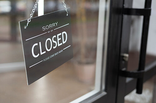 A sign hanging in a shop door window reading "Sorry we are closed"